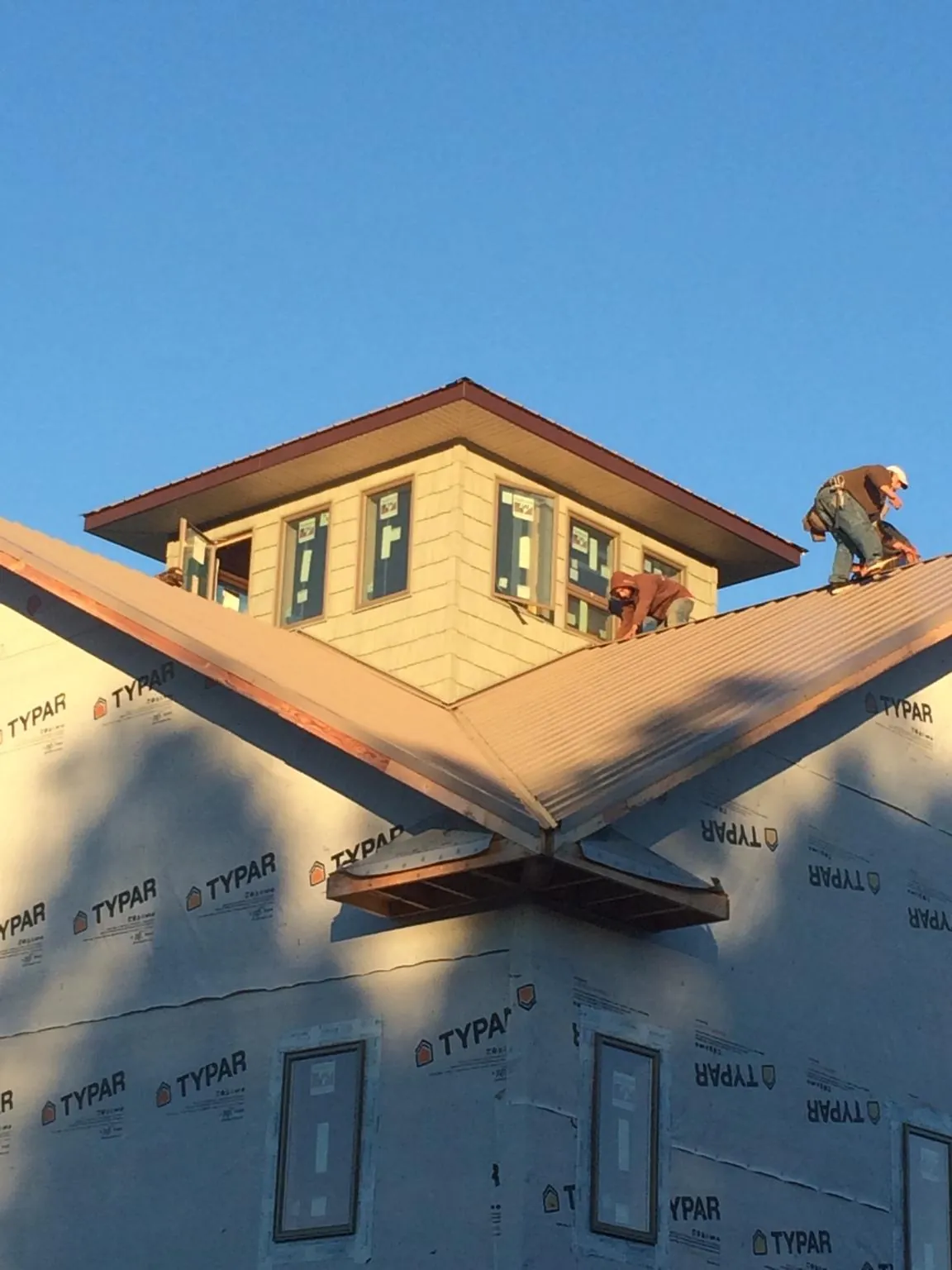 Roofers working around a rooftop cupola on a new metal roof at sunset — Roof Waterproofing in Stapleton by Roofing Brothers